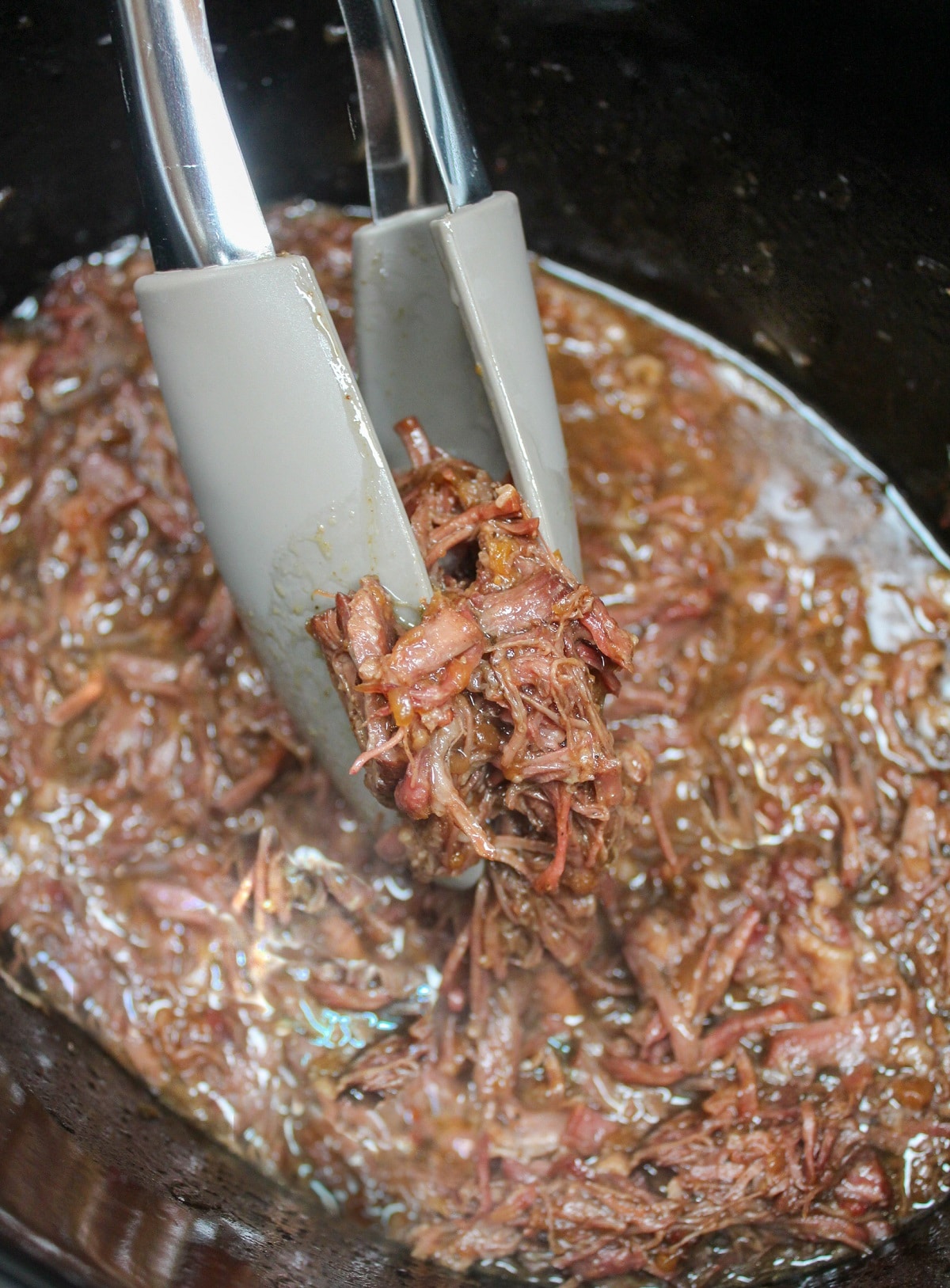 shredded beef held with tongs