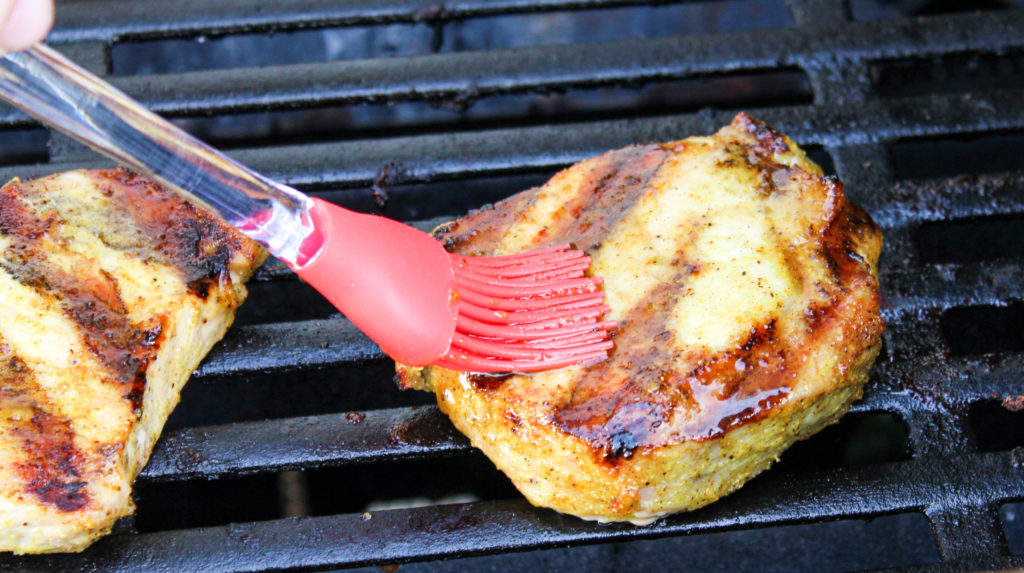 pork chops on the grill brushed with sauce