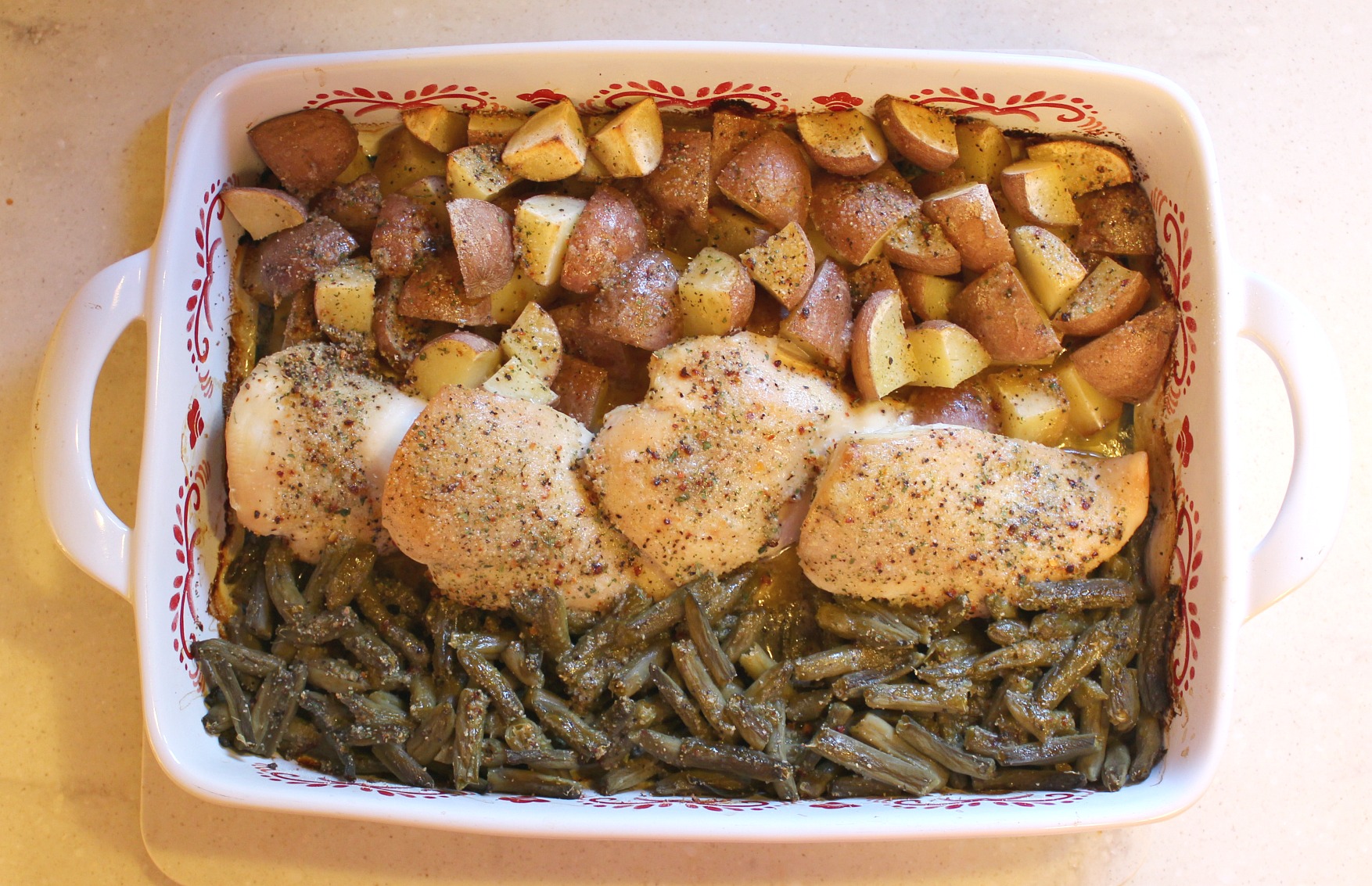 chicken in a baking dish with potatoes and green beans 