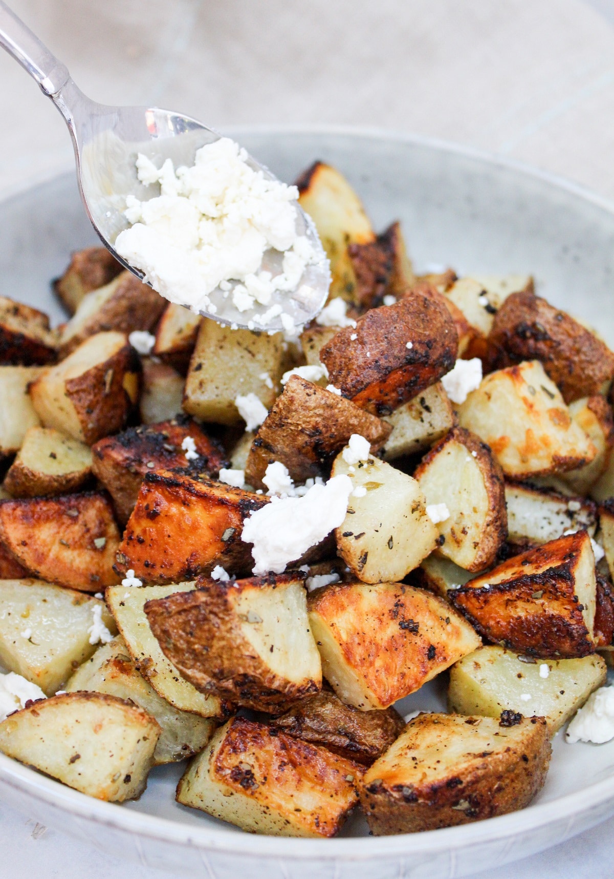 Roasted Potatoes with Lemon, Oregano and Feta sprinkled on top with a spoon
