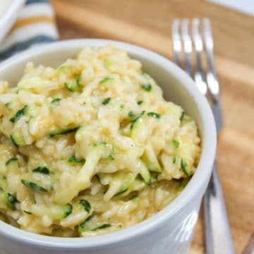 cooked cheesy zucchini rice in a bowl with a fork on the side