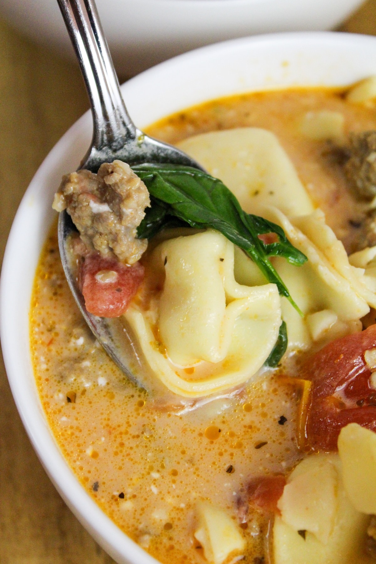 overhead picture of tortellini and sausage soup on a spoon