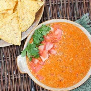 slow cooker chorizo queso dip with tomatoes and cilantro with chips on the side