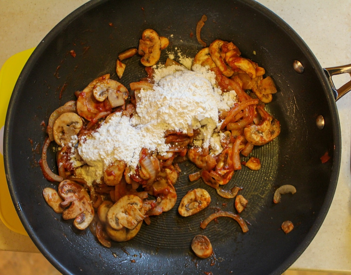 mushrooms and onions in pan with tomato paste