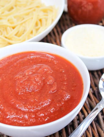 marinara sauce in a bowl with pasta in the background