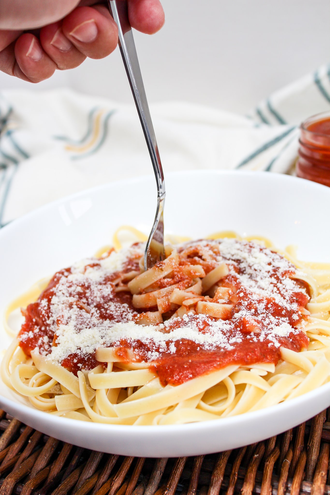 pasta sauce spooned over cooked pasta with parmesan cheese and a fork