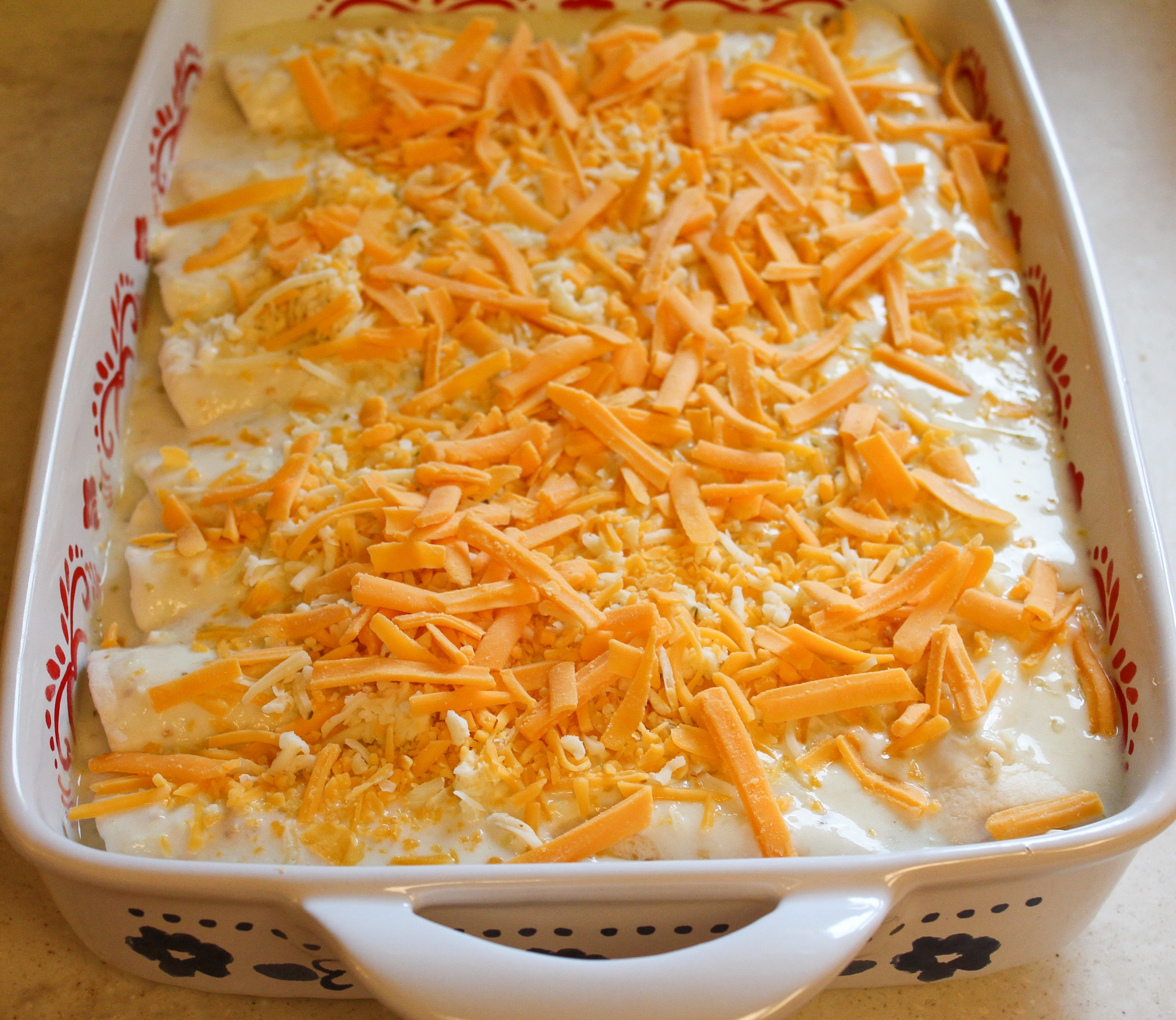 enchiladas in a baking dish with sauce and cheese
