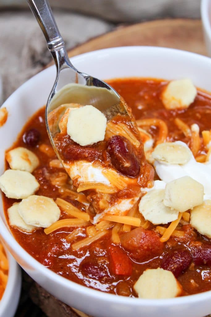 chili on a spoon with sour cream, cheese, and crackers
