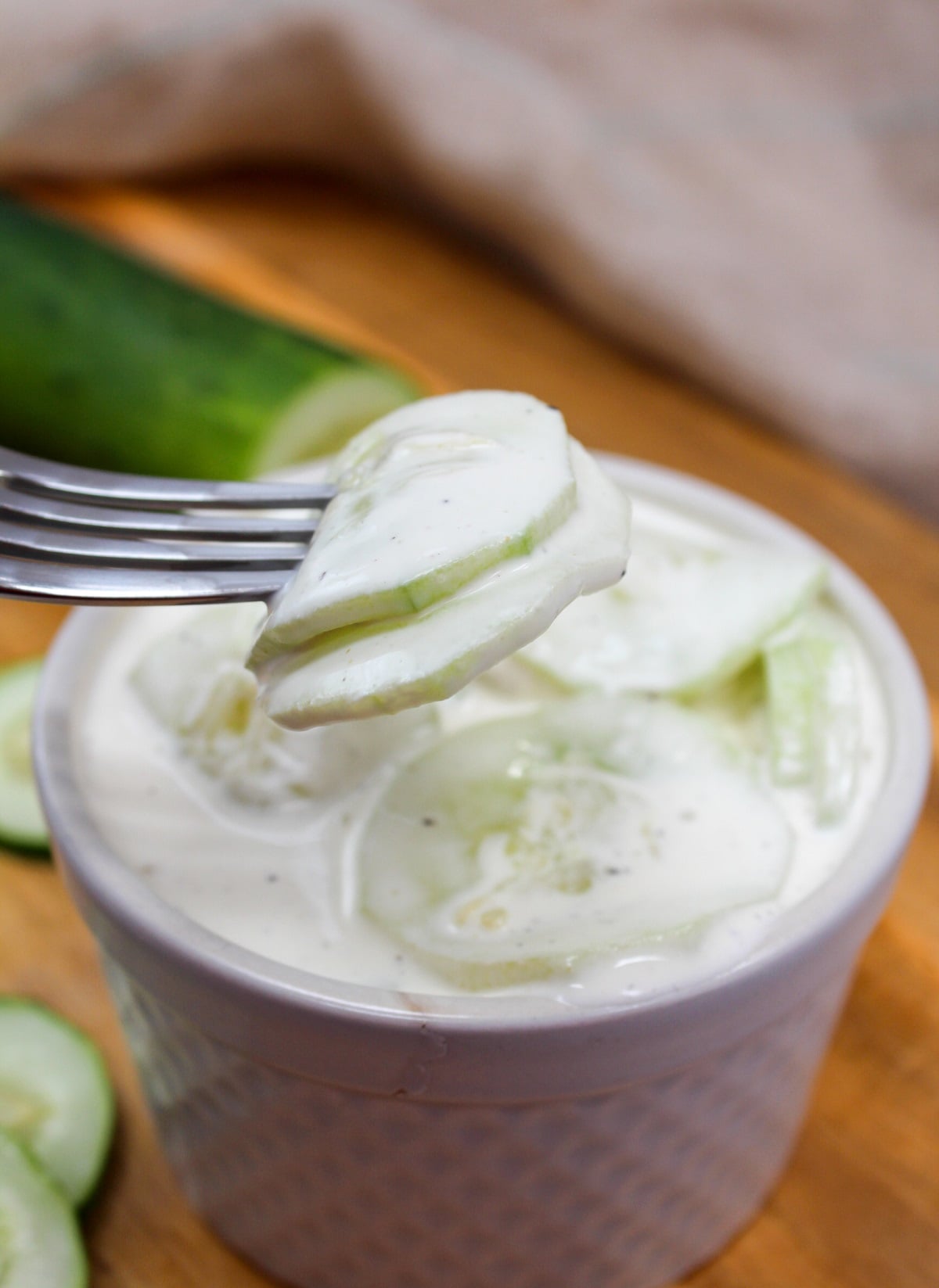 creamy cucumbers in a white bowl and with a fork