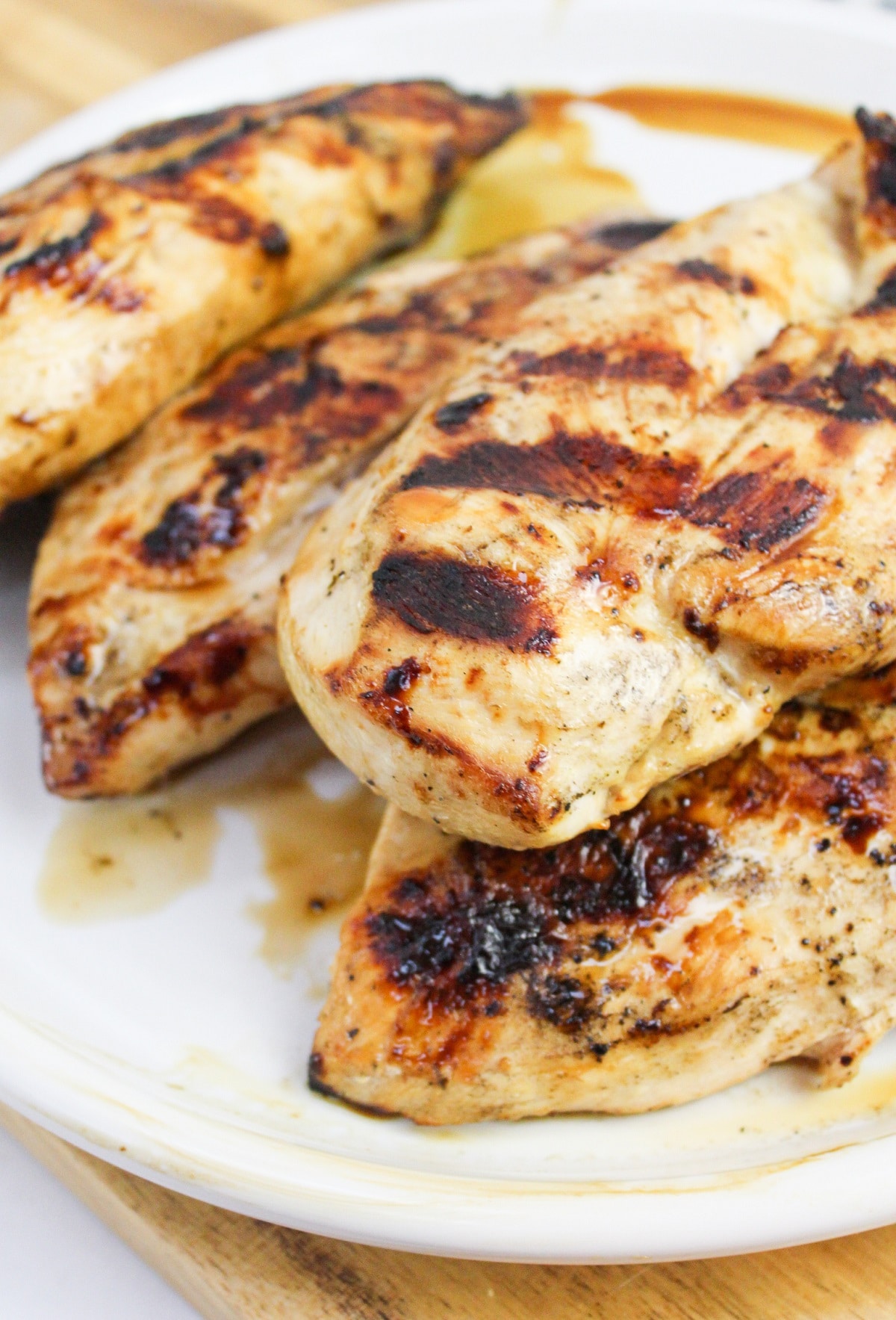 Grilled greek chicken stacked on a white plate.