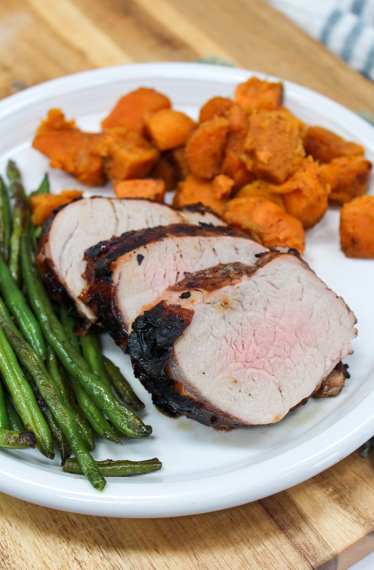 Grilled Honey Balsamic Pork Tenderloin grilled and sliced on a plate with sweet potatoes.