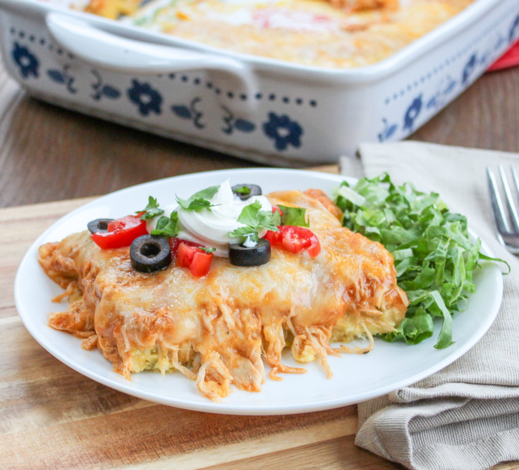 Portion of chicken tamale casserole with cheese on a plate with a side salad