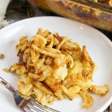 cheesy potato casserole on a white plate with a fork