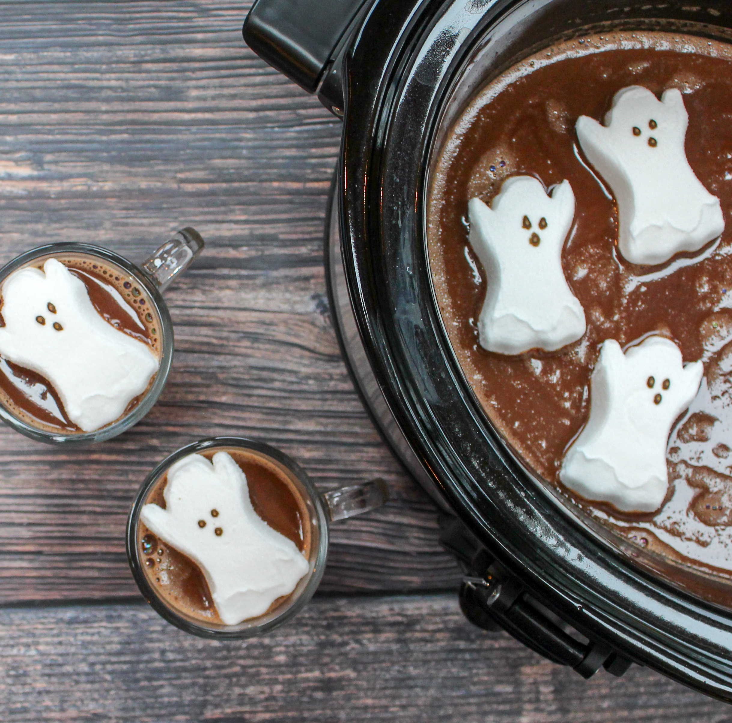 glasses filled with hot chocolate and topped with a ghost shaped marshmallow