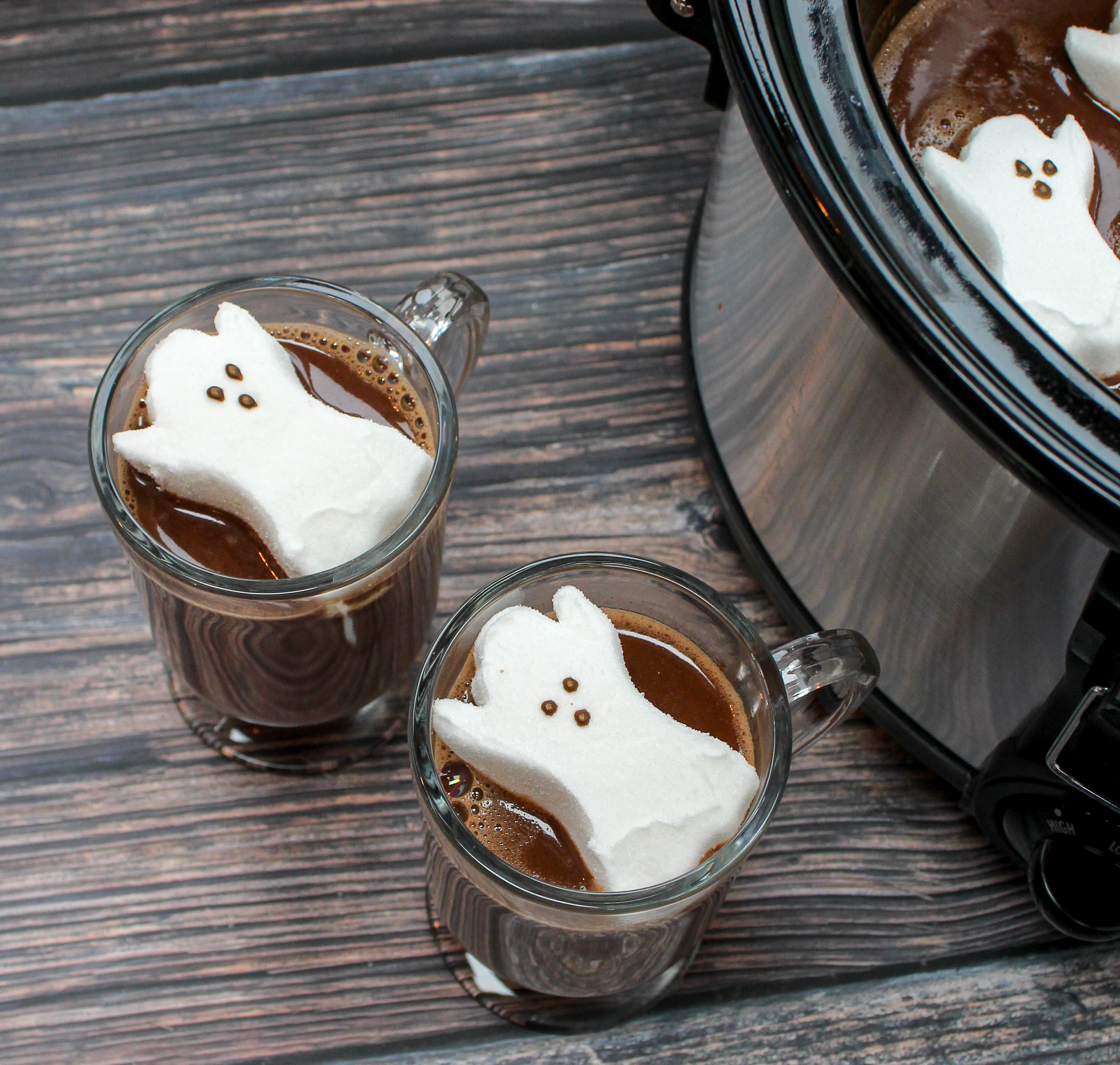 glasses filled with hot chocolate and topped with a ghost shaped marshmallow
