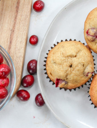 Several Muffins on a plate with cranberries on the side