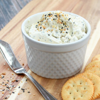 Spread in a white container wth crackers and a spreading knife