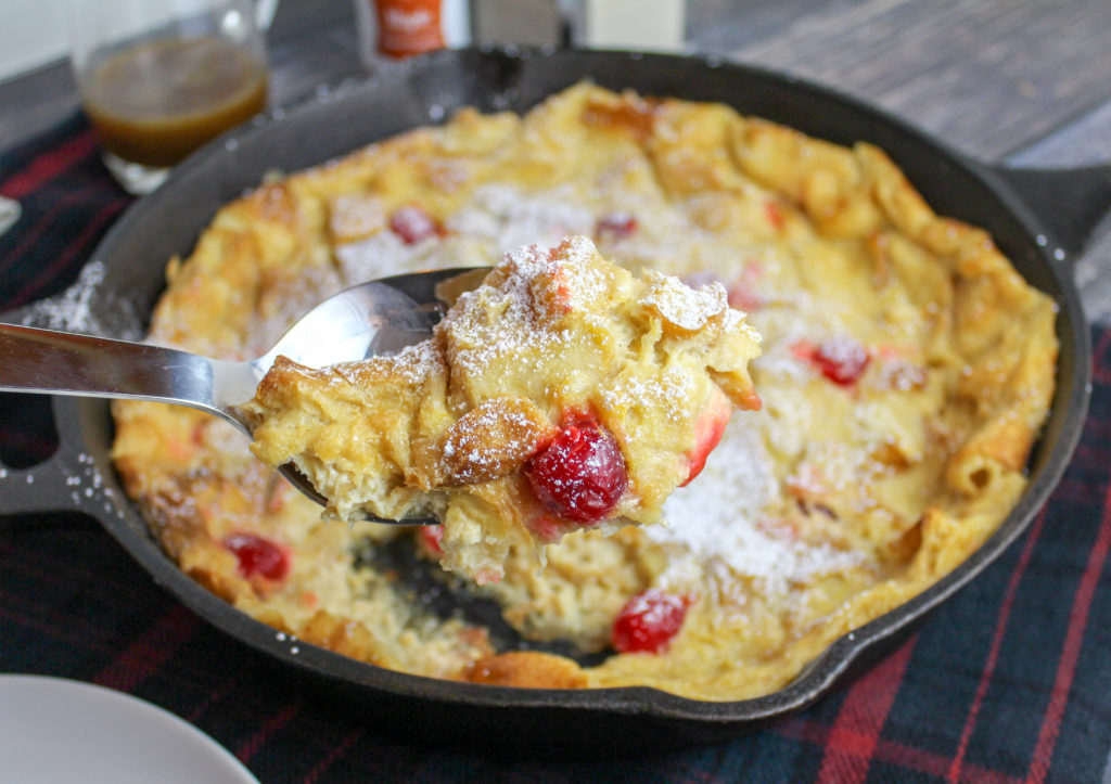 Bread pudding studded with cherries in a cast iron pan
