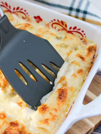 Chicken enchiladas in a baking dish with a spatula