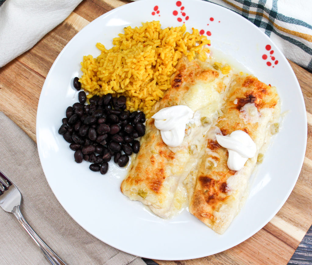 Chicken enchiladas on a plate with rice and beans