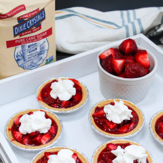 mini strawberry pies on a platter with whipped cream