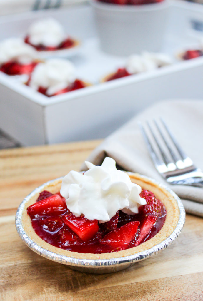 mini strawberry pies on a platter with whipped cream