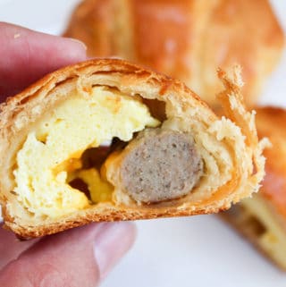 roll-up cut in half to see eggs and sausage and held in hand