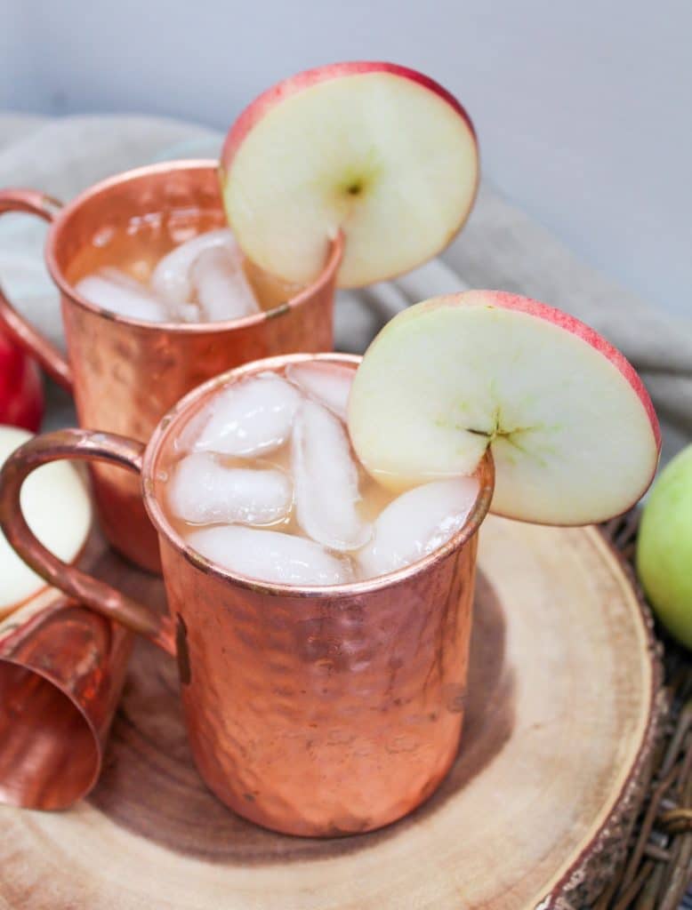 apple cider mule in a copper mug with an apple slice as a garnish