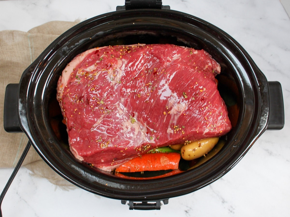 uncooked corned beef in a slow cooker