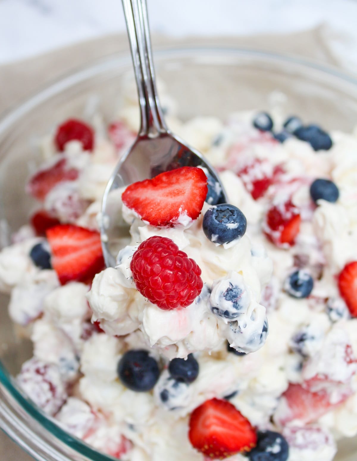 salad on spoon showing strawberries, blueberries, and raspberries