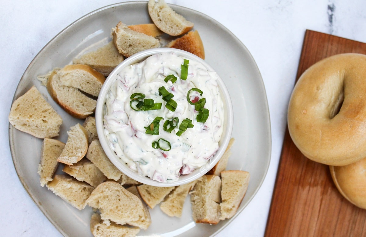bagel dip in a white dish with bagel pieces on the side