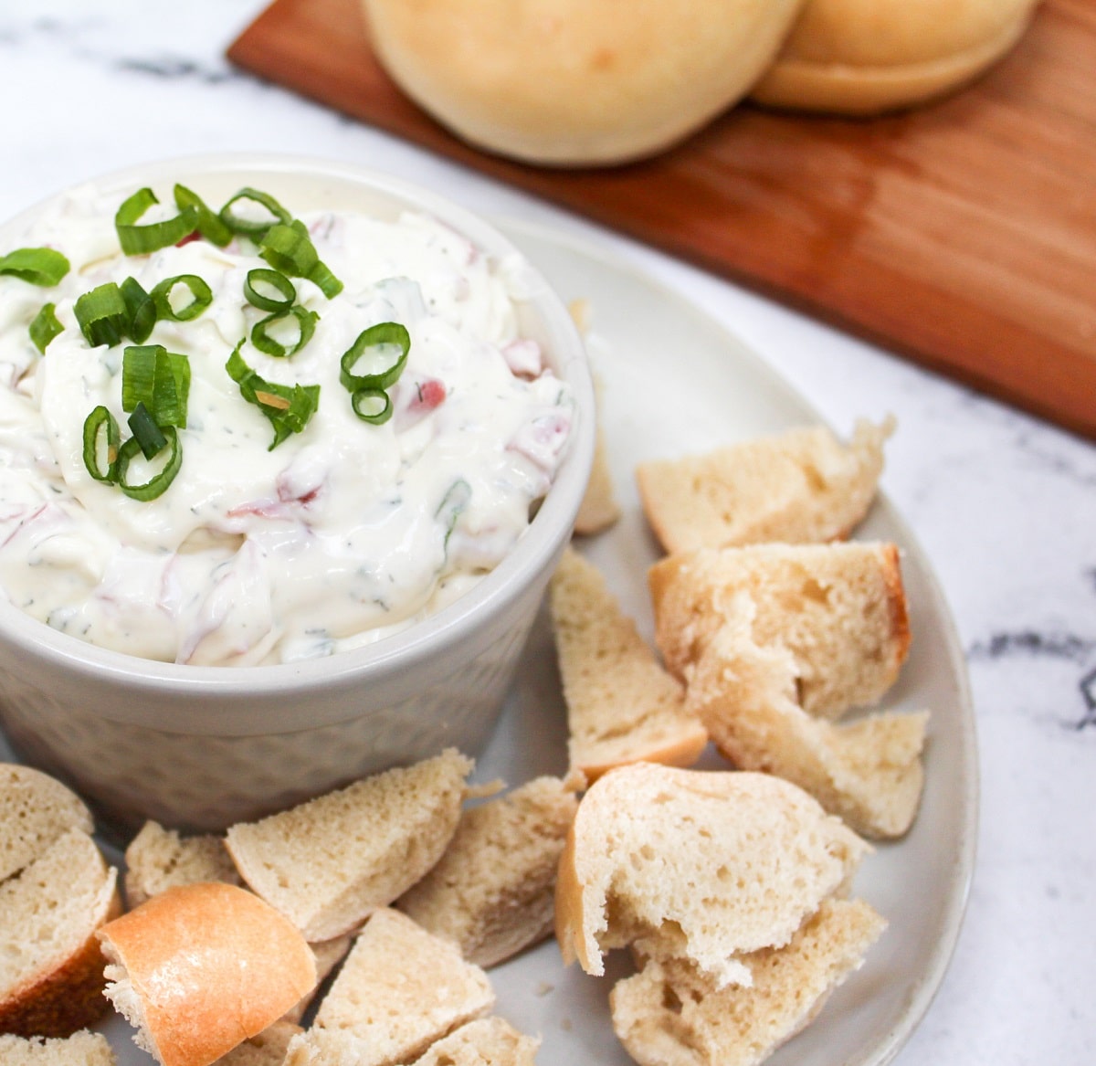 bagel dip in a white dish with bagel pieces on the side