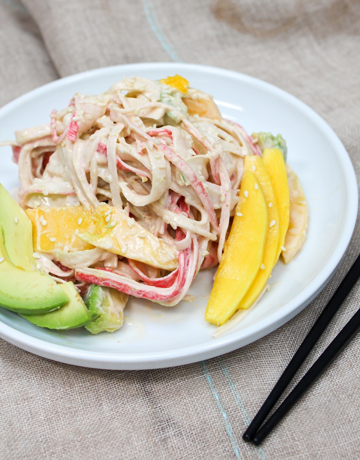 spicy kani salad on a plate with mango and avocado slices