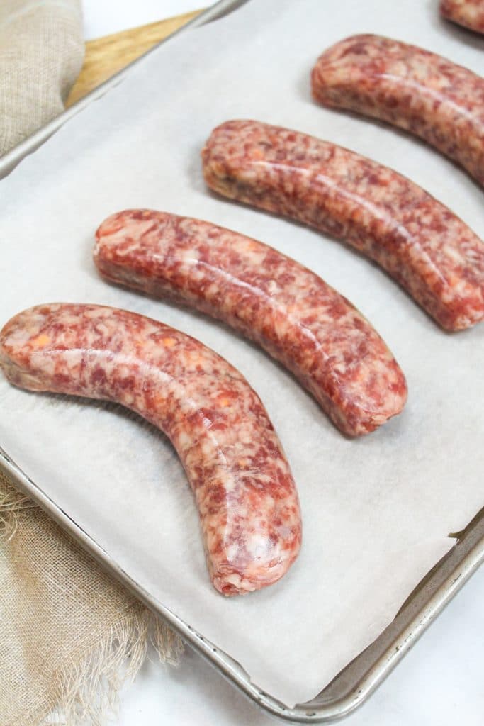 uncooked brats on a baking sheet