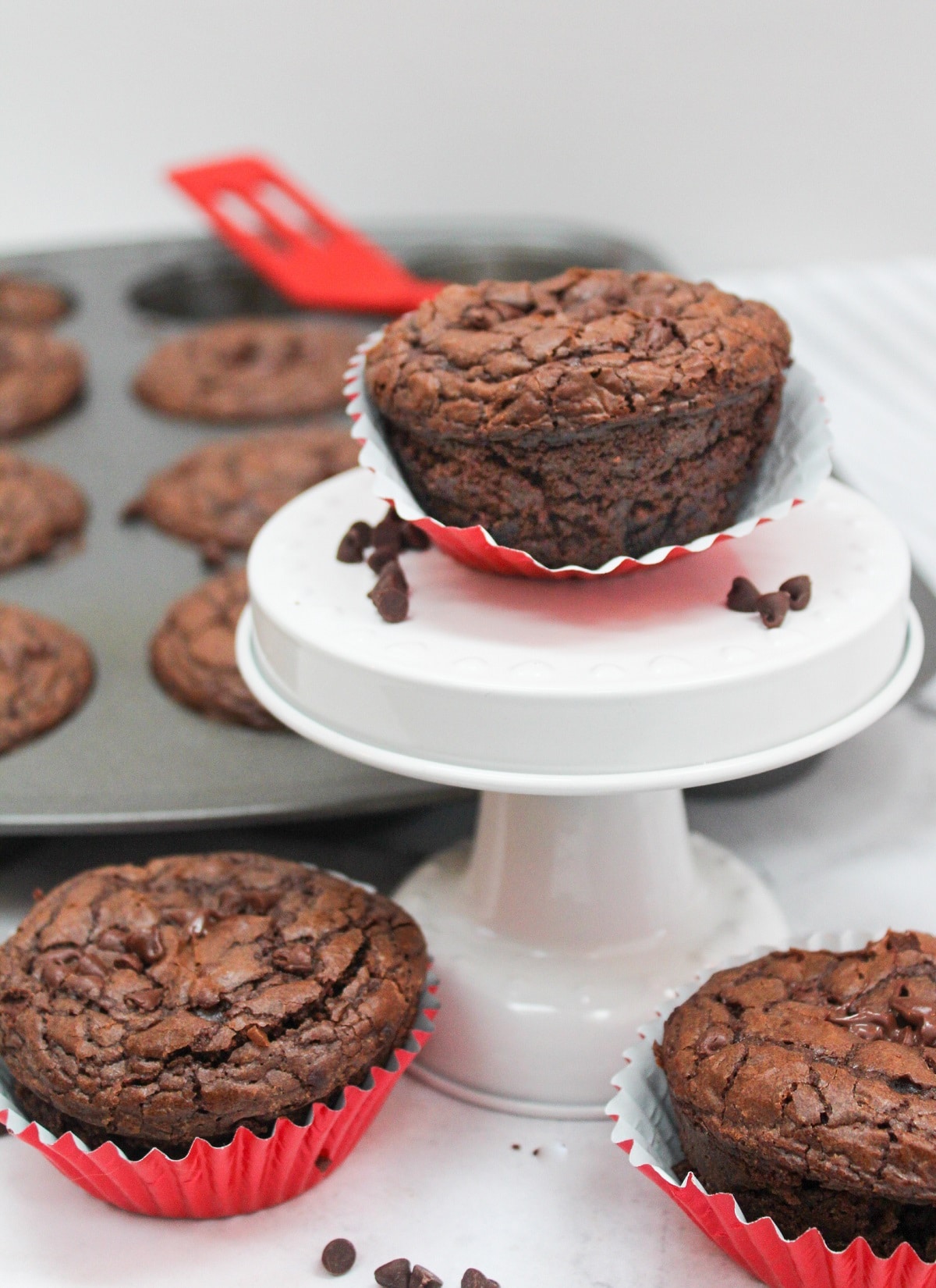 brownie muffins on a white plate with other in a muffin tin to the side