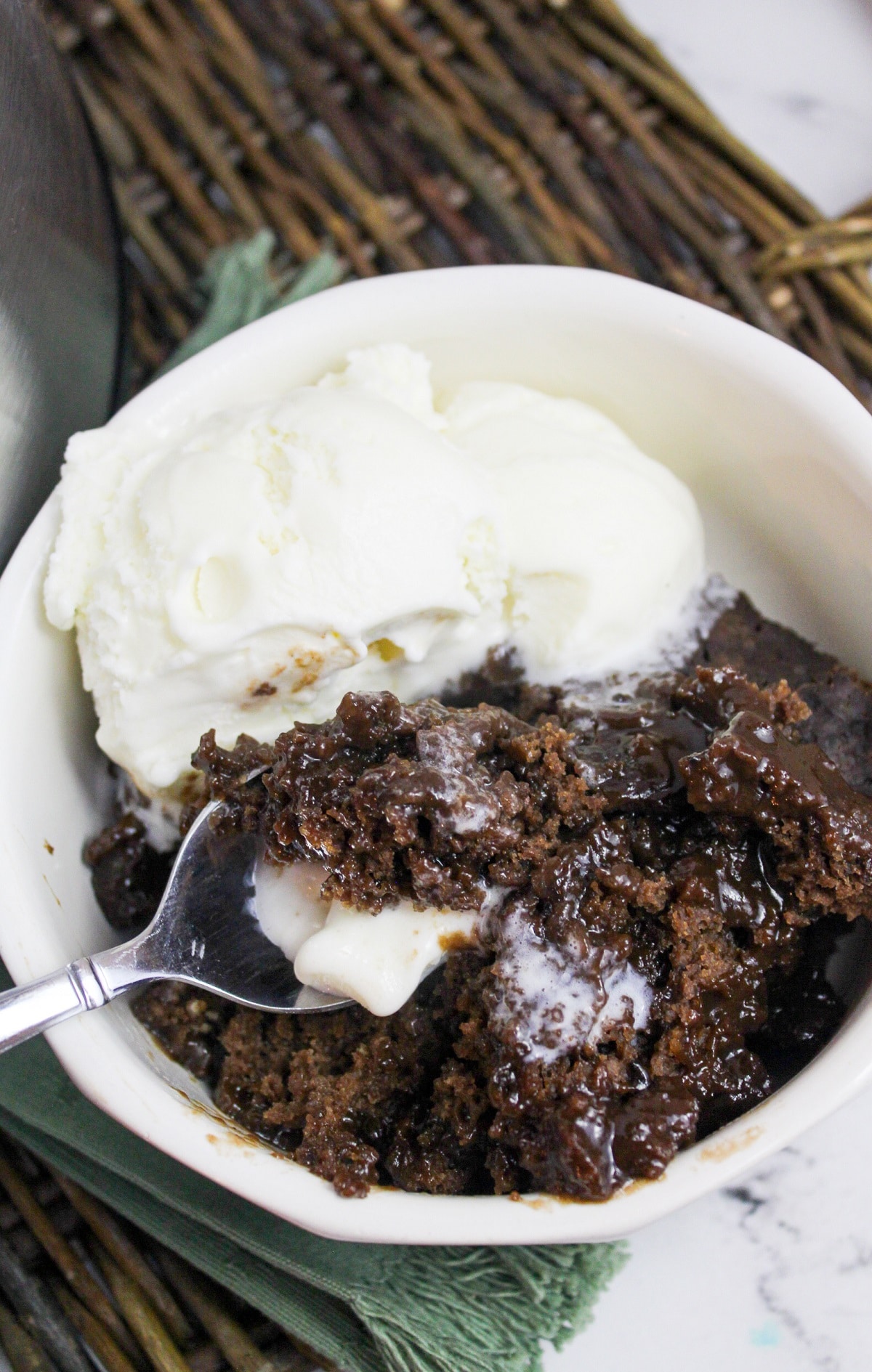 slow cooker chocolate cobbler in a bowl with vanilla ice cream with spoon