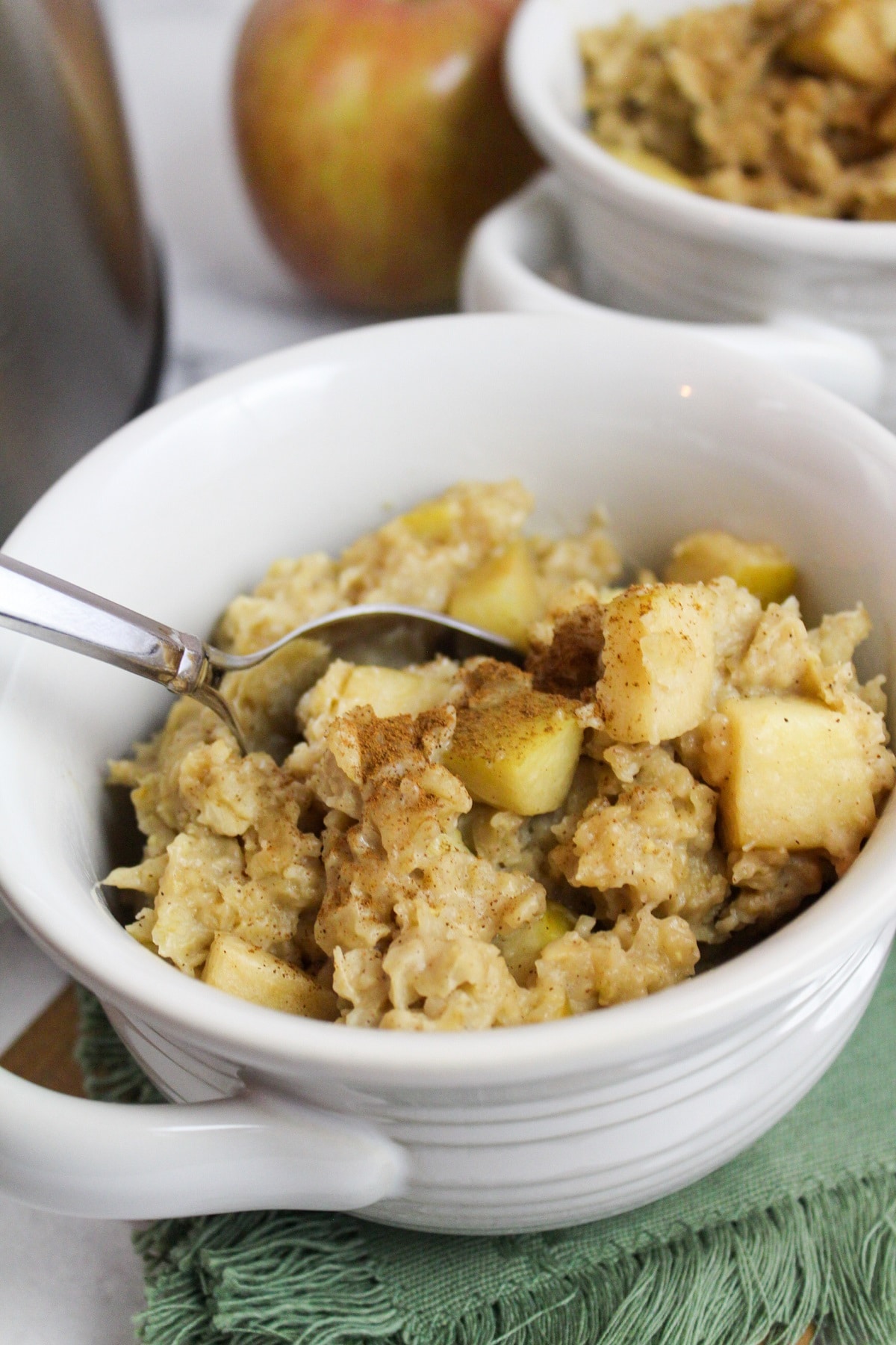 slow cooker apple cinnamon oatmeal with a spoon in a white bowl