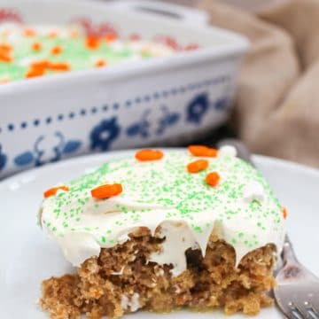 carrot cake poke cake on a white plate with a fork