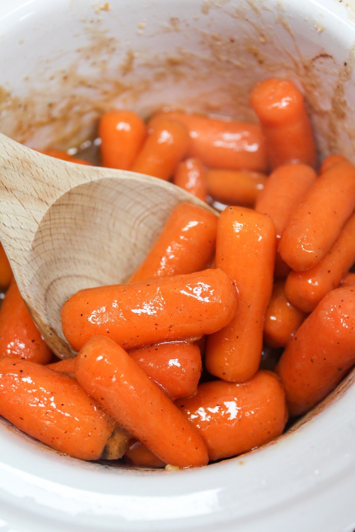 slow cooker brown sugar carrots in slow cooker with a wooden spoon