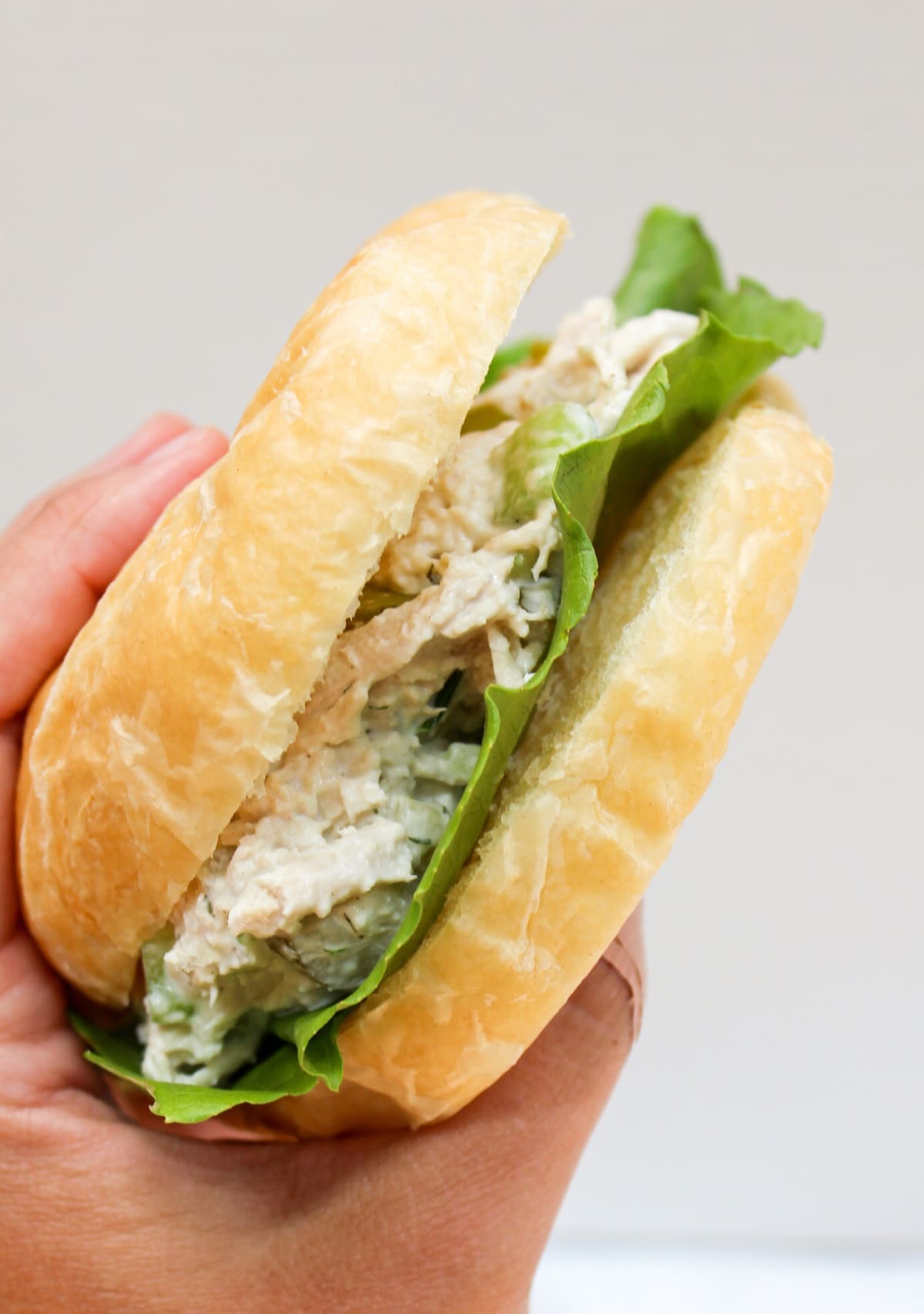 dill pickle chicken salad on a croissant held in hand