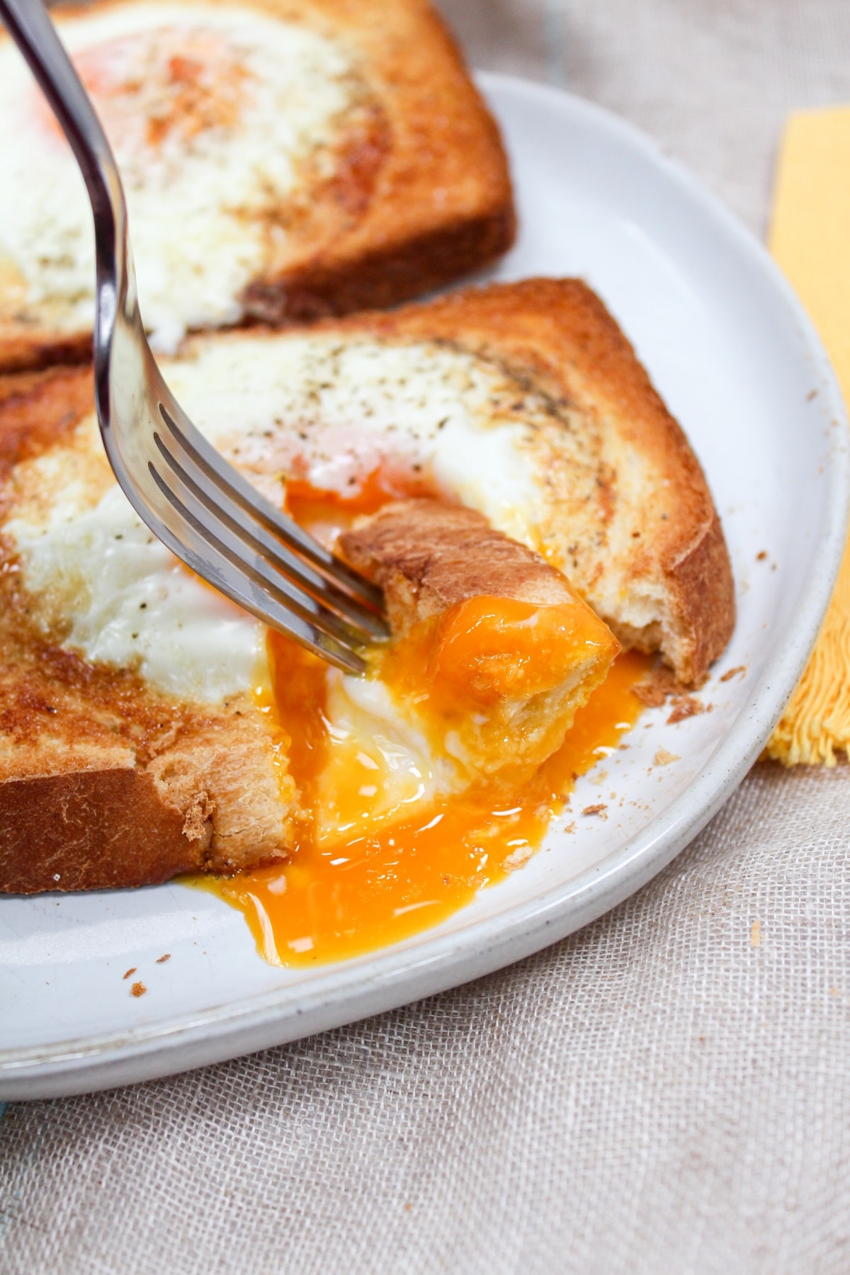 air fryer egg toast on a plate with yolk broken and a fork