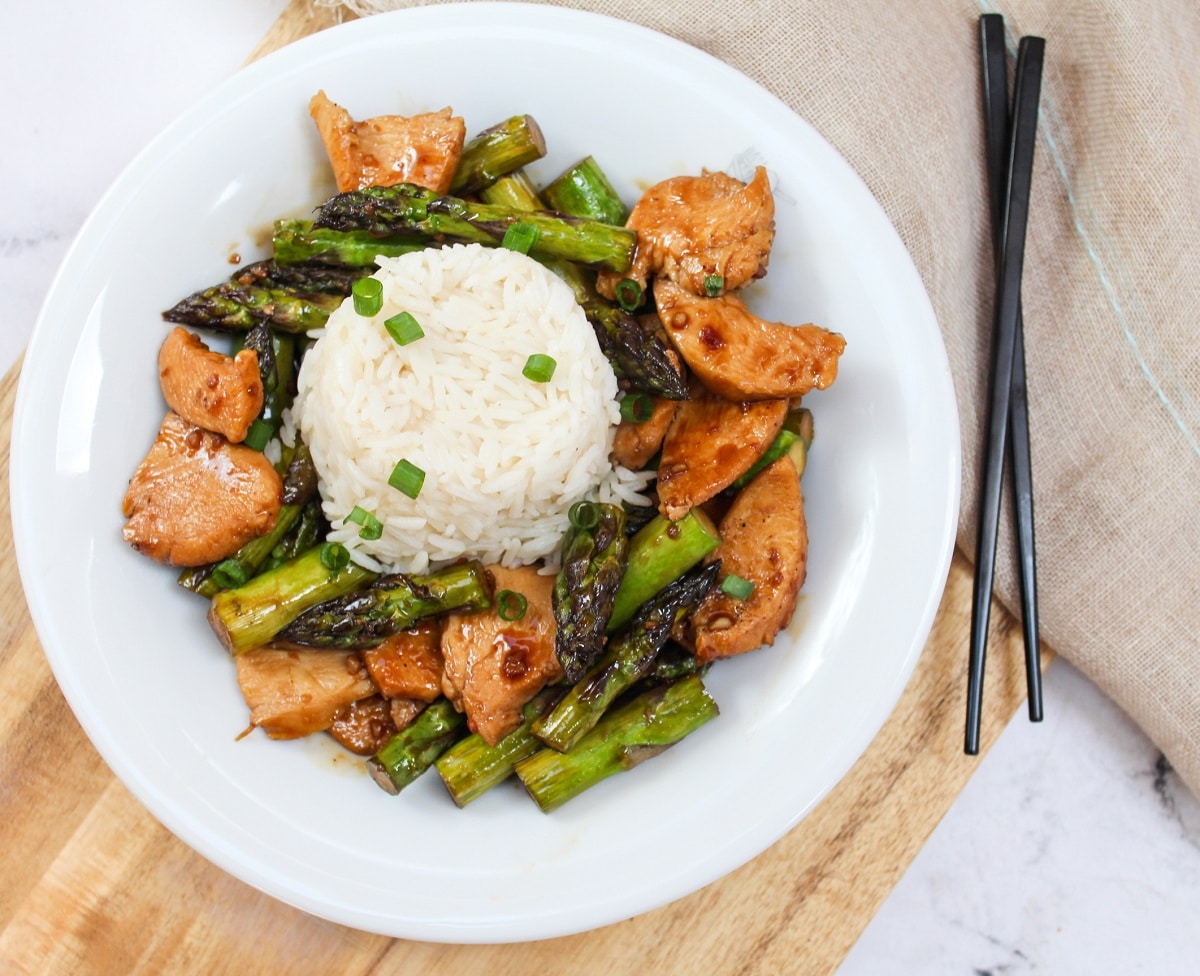 chicken and asparagus stir fry in a bowl with rice.