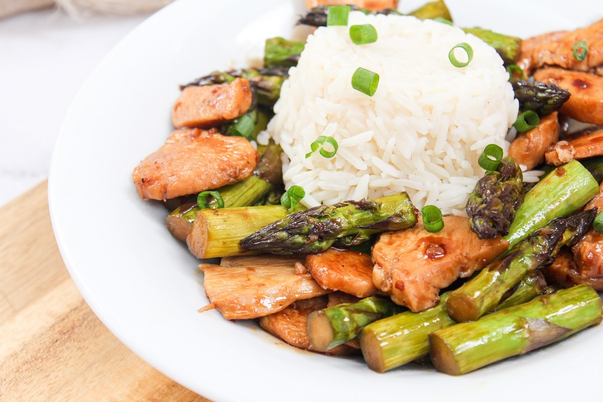 chicken and asparagus stir fry in a bowl with rice.
