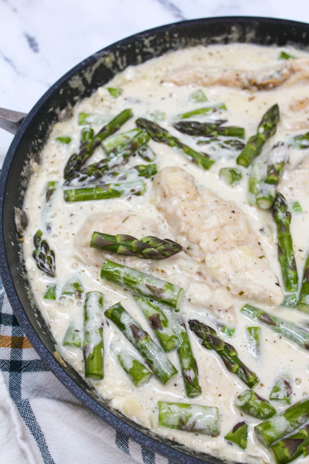 creamy keto chicken and asparagus in a skillet.