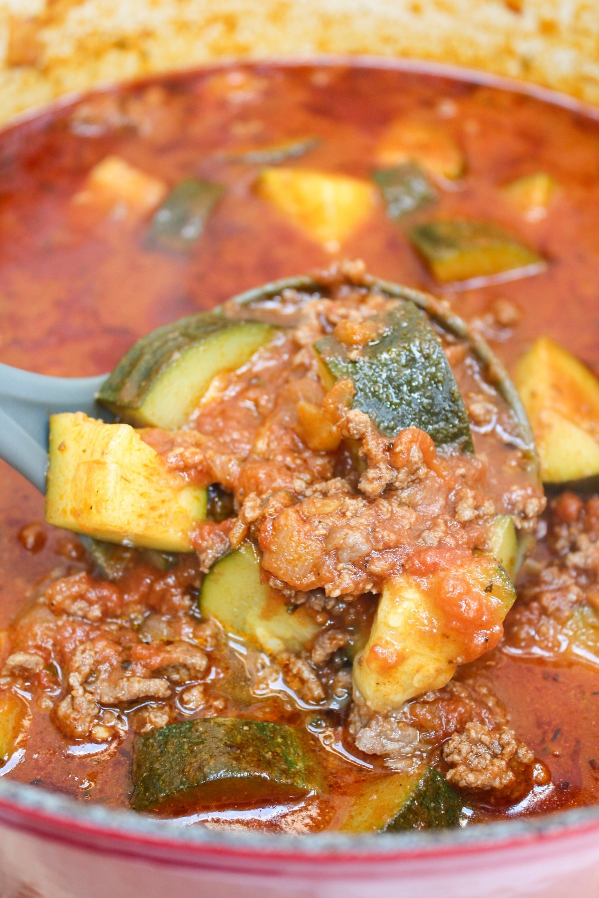 zucchini and hamburger stew ladled from a stew pot.