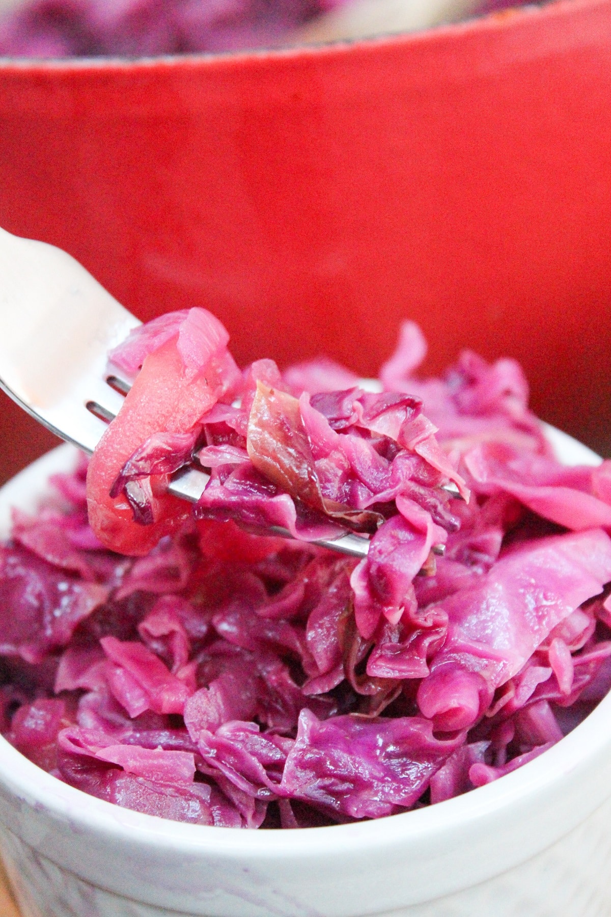 chopped red cabbage and apples in a small white dish with a fork.