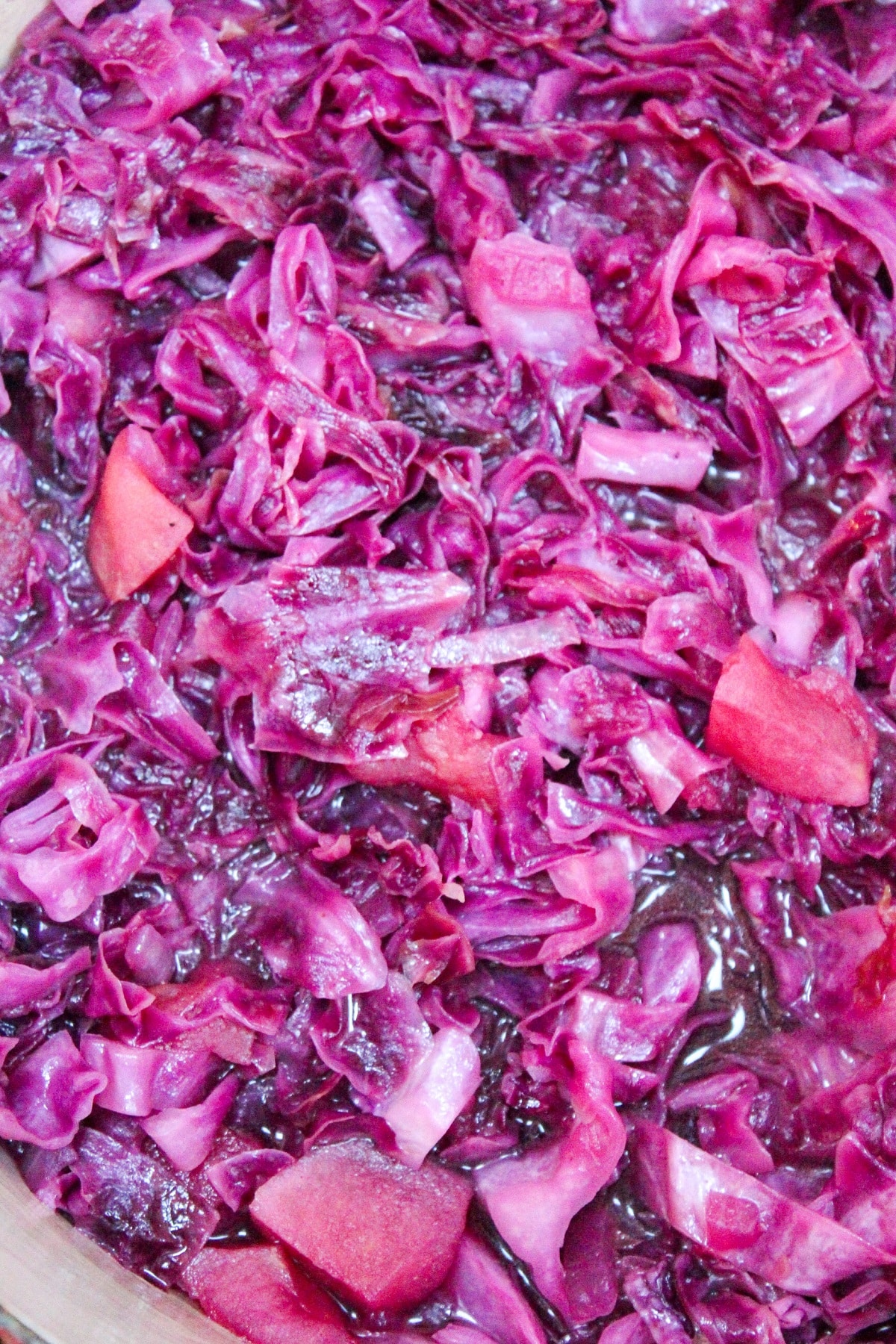 chopped red cabbage and apples in a red pot.