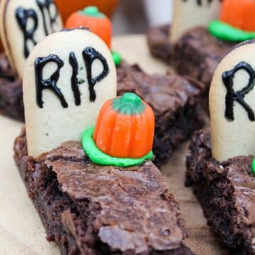 brownies cut into long pieces. Topped with a cookies with the letters RIP. A candy pumpkin and green frosting is next to the gravestone.