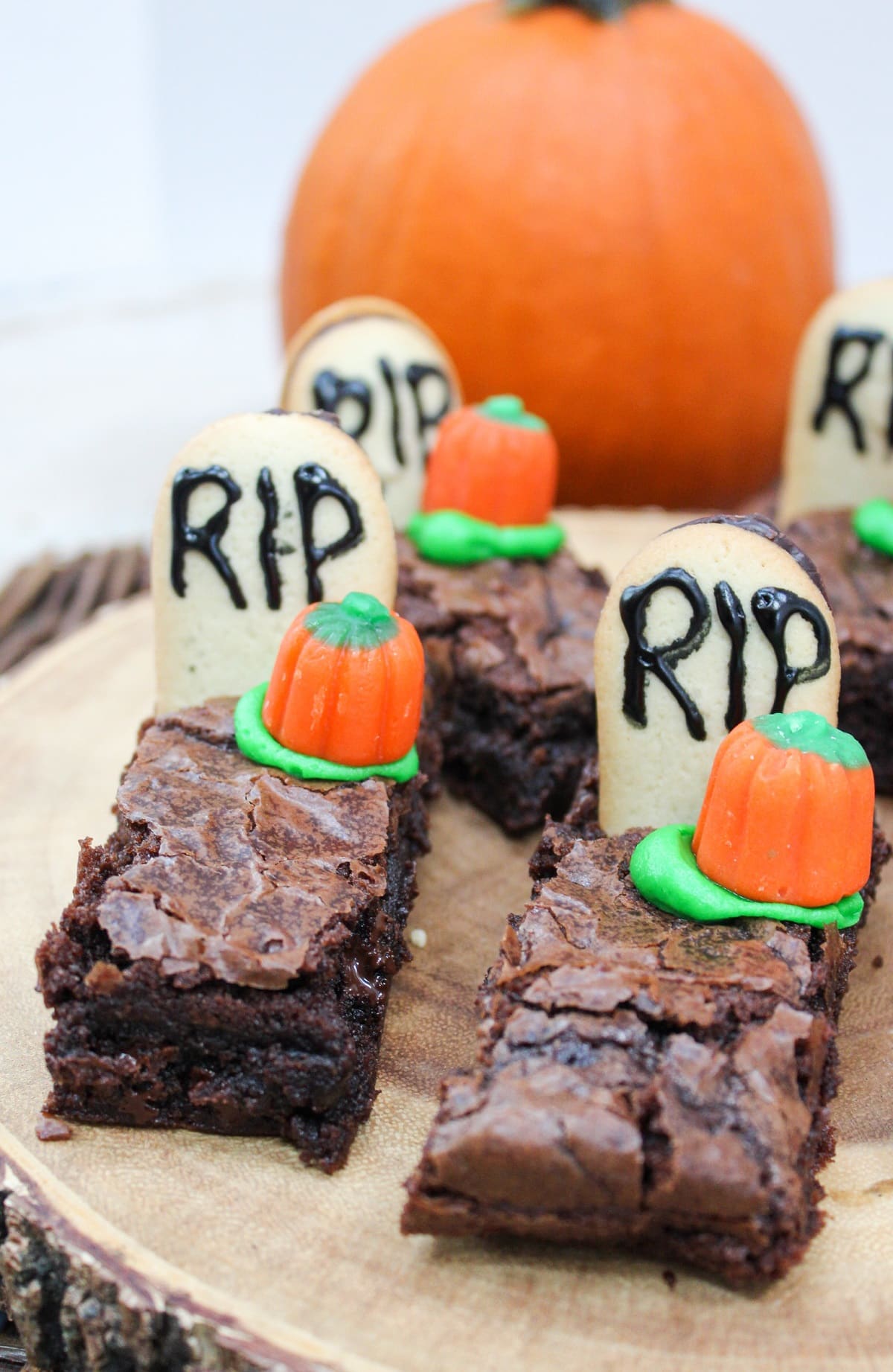 brownies cut into long pieces. Topped with a cookies with the letters RIP. A candy pumpkin and green frosting is next to the gravestone.