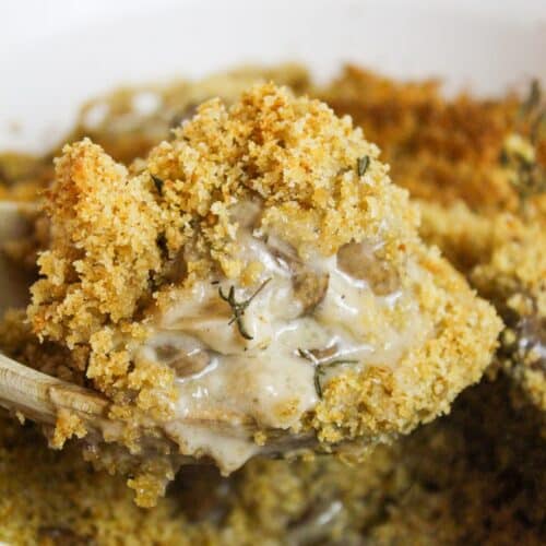 creamy mushrooms baked with a breadcrumb topping lifted from the dish with a spoon.